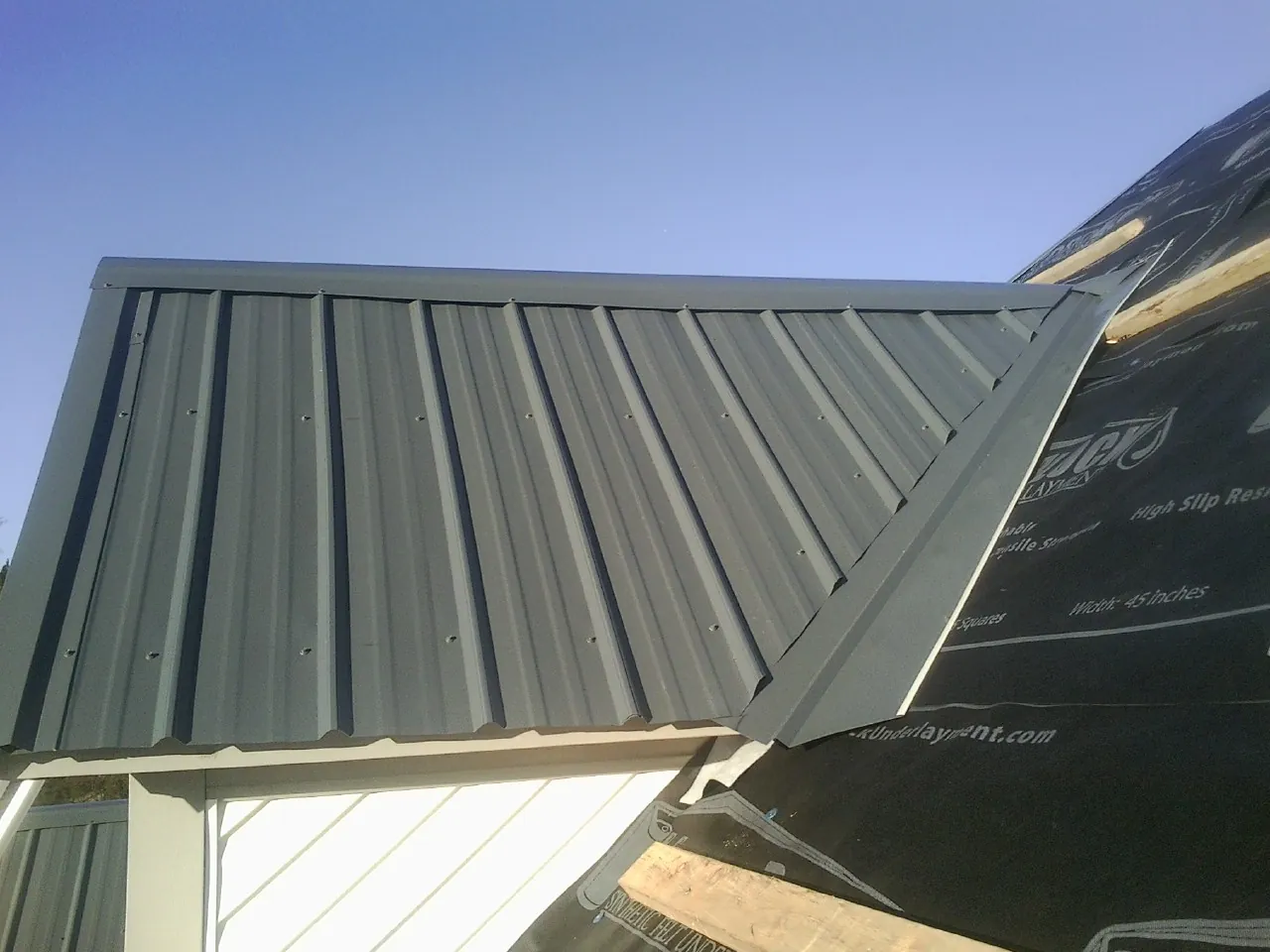 Gray metal roof panels going on over a garage gable in Hinton