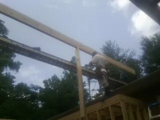Carpenter setting a ridge beam over a new addition frame — Ice Dam Removal by Roofing Brothers in Hinton