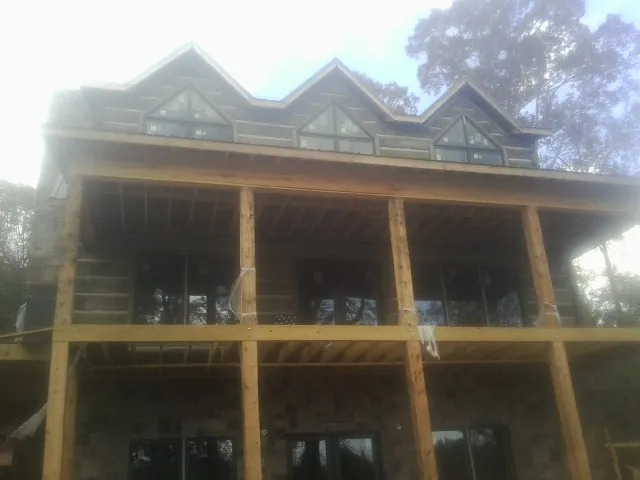 Dormers and porch framing on a large log home under construction — Roof Coating work by our crew in Hinton